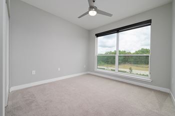 A room with a ceiling fan and a window overlooking a green landscape at Ironwood Flats Apartments, Florida, 33511